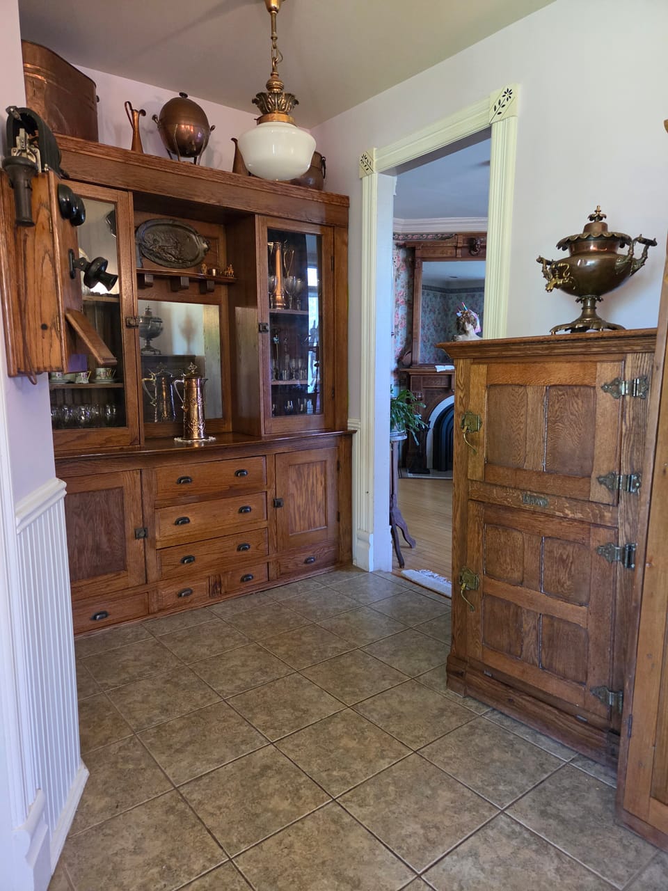 Built-in hardwood hutch with glass display cabinets, brass-pull drawers, and pocket doorway